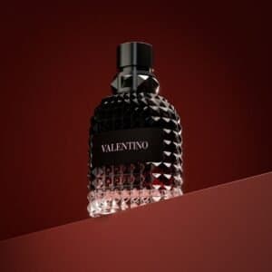 a bottle of perfume sitting on top of a red surface